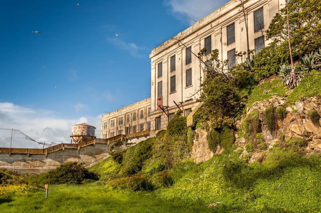 Alcatraz Island prison building perched on the rocky hillside under a blue sky