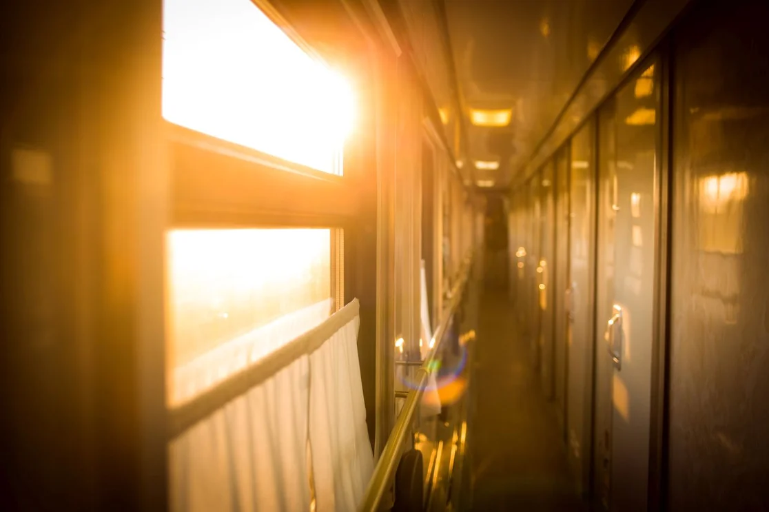 Golden sunrise flooding through the corridor windows of a sleeper train
